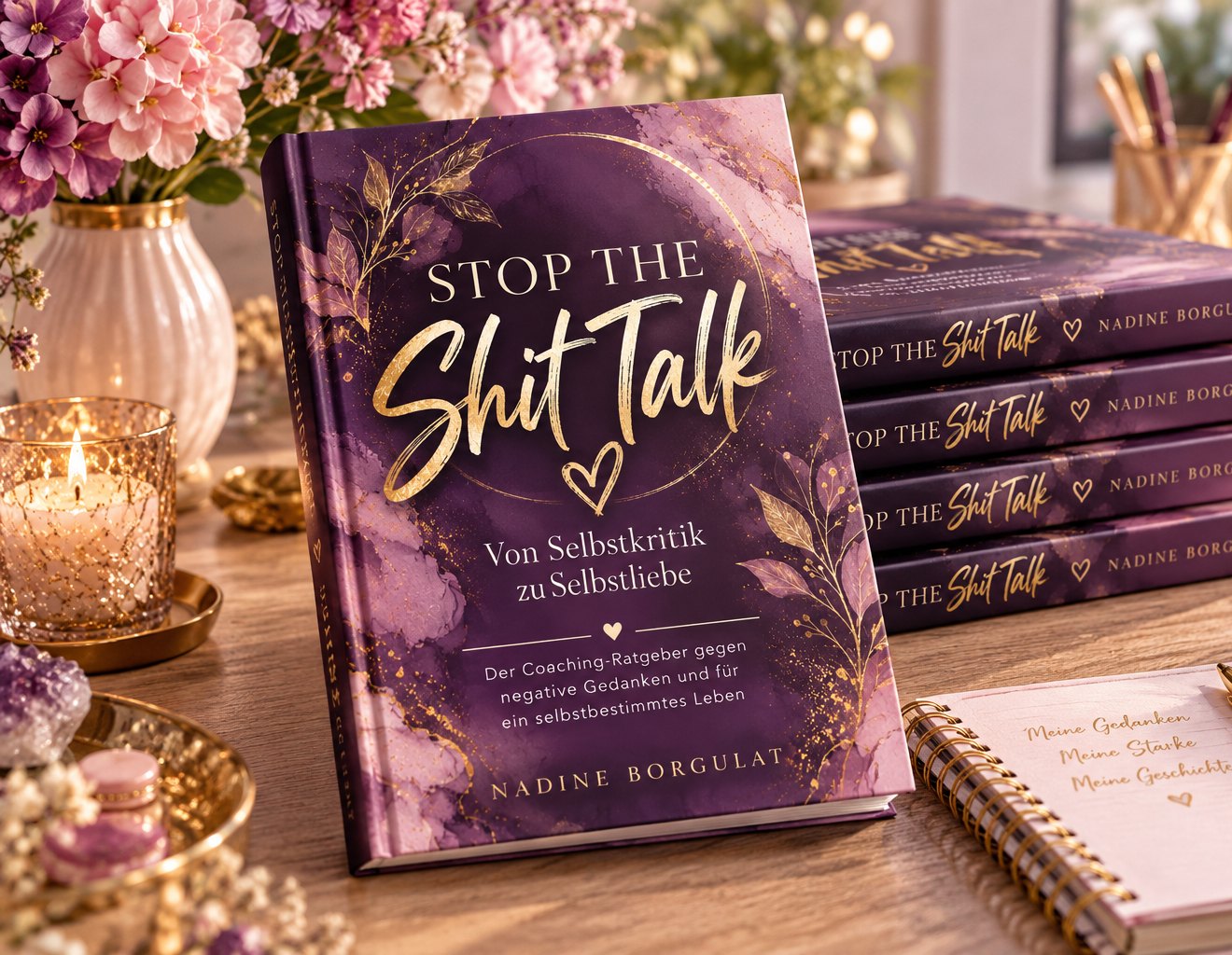 Das Buch Stop the Shit Talk auf einem Schreibtisch mit Blumen, Kerze und Notizbuch